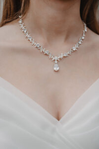 Frau  ohne  Gesicht,  neutral,  weisses  Kleid,  silbernes  Blumenhalsband  mit  Tropfen